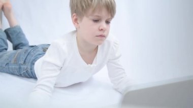 Sarışın çocuk bilgisayar veya dizüstü bilgisayar ekranına dikkatle bakar. Yakın plan portre