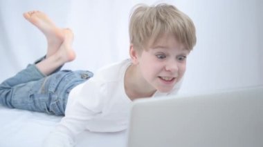 Sarışın çocuk bilgisayar veya dizüstü bilgisayar ekranına dikkatle bakar. Yakın plan portre