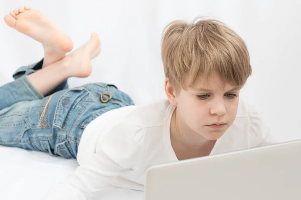 Blonďaté dítě se pozorně podívá na monitor počítače nebo notebooku. Detailní záběr portrétu — Stock fotografie