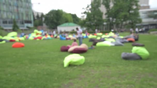 Θολή Υπόβαθρο άνθρωποι ξεκουραστούν χαλαρώστε στην καρέκλα τσάντα, πολυθρόνες τσάντες στο πάρκο — Αρχείο Βίντεο