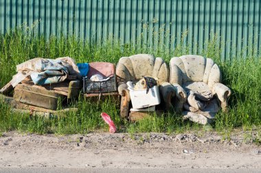 Yolun kenarında diğer çöplerle birlikte eski bir kanepe duruyor. Çöp öğütülmeye hazır.