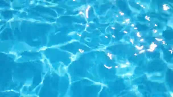 El movimiento del agua en la piscina, vista superior. Fondo, textura. Agua azul clara en la piscina bajo el sol — Vídeos de Stock