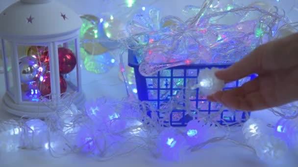 Zbliżenie ręki kupujących. Klient wybiera lampki świąteczne i sprawdza je na ladzie. Koncepcja wyboru dekoracji na Boże Narodzenie i Nowy Rok. wybór wysokiej jakości świąt Bożego Narodzenia — Wideo stockowe