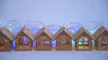 Güzel ahşap çelenkler sıraya dizilmiş. Noel ışıkları ve çelenkler evlerin arkasında yanıp sönüyor. Güzel büyülü gece aydınlatması. Noel ve yeni yıl hazırlık konsepti. Ev