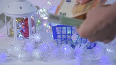 Alışverişçilerin elini kapat. Müşteri Noel ışıklarını seçer ve onları tezgahta inceler. Sonra da AB faturalarıyla ödüyor. Noel ve Yeni Yıl için dekorasyon seçimi konsepti