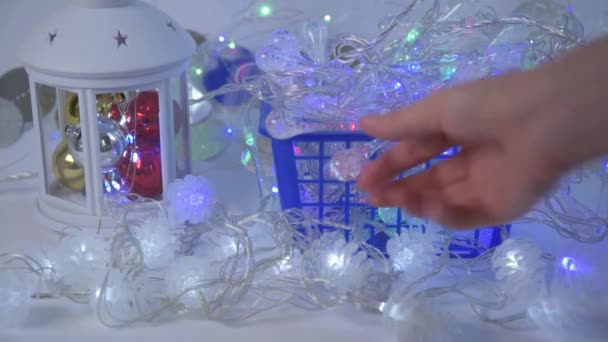 Zbliżenie ręki kupujących. Klient wybiera lampki świąteczne i sprawdza je na ladzie. Potem płaci unijnymi rachunkami. Koncepcja wyboru dekoracji na Boże Narodzenie i Nowy Rok — Wideo stockowe