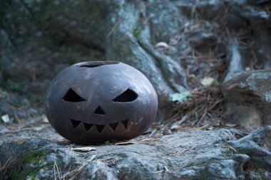 Cadılar Bayramı balkabağı kilden yapılır. Ağaç köklerinin arka planında korkunç korkunç bir balkabağı