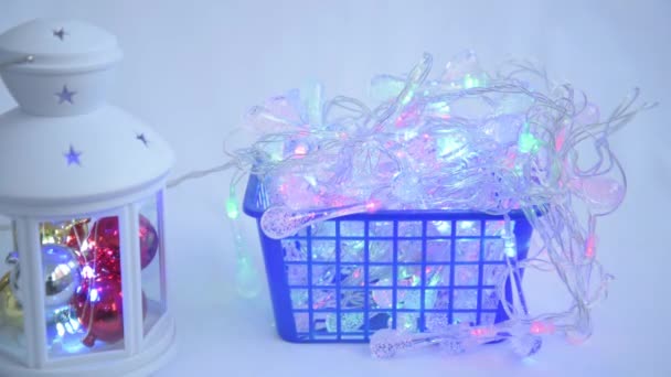 Guirlandes de Noël clignotant avec différentes lumières. Lanterne avec jouets du Nouvel An. Les guirlandes sont dans un panier. Concept de préparation de Noël — Video