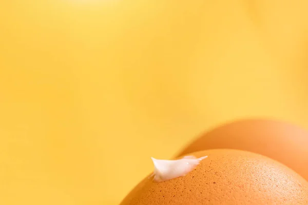 創造的な日焼け止めの概念 太もものような茶色の卵 フロントバトックにクリームのドロップ 壮大な影を持つ黄色の背景 ミニマリズムマクロ — ストック写真