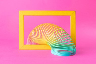 Pastel pembe arka planda oyuncak plastik gökkuşağı. 90 'larda popüler olan oyun ve dublörler için renkli bir spiral. Minimalizm. Oyuncaklar, çocukluk kavramı. parlaklık.