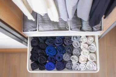 Gardıropta yer düzenleme kavramı. Koyu ve açık renkli giysiler güzelce asılır ve dolaba saklanır..