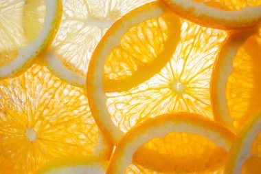 Aşağıdan aydınlatılmış portakal ve limon dilimleri. Parlak narenciye arkaplanı. Sağlıklı yaşam tarzı, vitaminler, düzgün beslenme, diyet, yaz, taze meyve suyu kavramı. Arkaplan meyve dokusu.