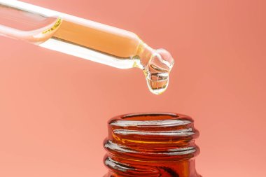 Pastel pembe arka planda gerekli yağı olan bir boru. Güzellik konsepti, cilt bakımı, aromaterapi, spa, kozmetoloji. Yakın çekim, detaylı makro fotoğraf.