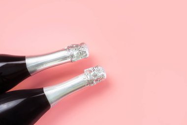 Pastel pembe arka planda gümüş folyolu şampanya şişesi boynu. Kutlama, tatil, yeni yıl konsepti. Minimalizm, boşluğu kopyala.