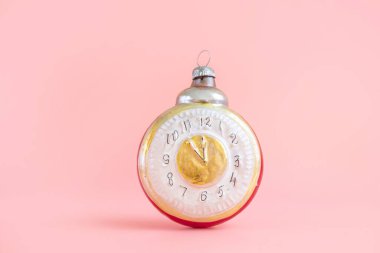 Eski yılbaşı oyuncağı, saat. Yeni yıl kutlaması, pastel pembe arka plan. Minimalizm. XX yüzyılı, antikalar..