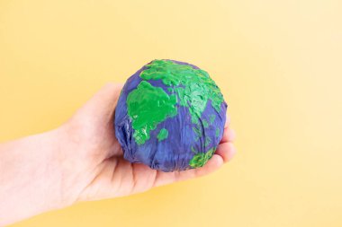 Ekoloji konsepti, çevre, plastiksiz, gezegeni kurtarmak. Plastik bir torbaya sarılı gezegenin modeli. Denizler ve kıtalar boyayla boyanmıştır. Buruşmuş Dünya gezegeni. Minimalizm, boşluğu kopyala.