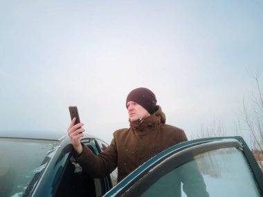 Genç bir adam kışın bir arabada kayboldu ve arabadan indikten sonra mobil şebekeyi yakalamaya çalışıyor. Kış yolculuğu, yol arama, seyrüsefer kavramı.