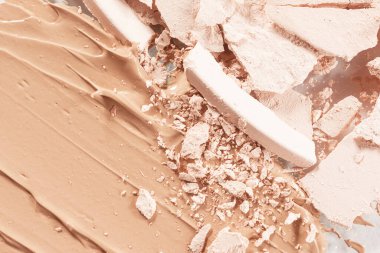 Loose light powder and smear of foundation close-up. The concept of decorative cosmetics, makeup. Advertising macro photography.	