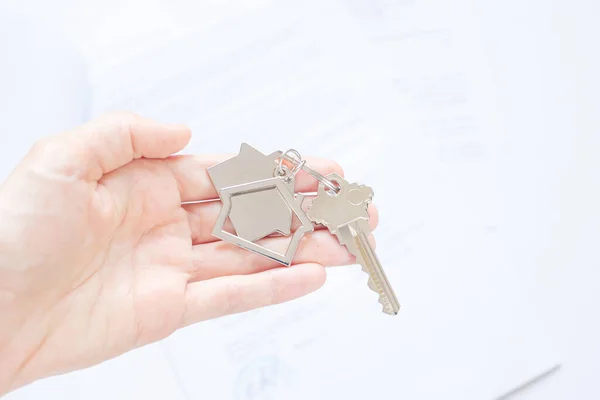 闭锁的钥匙与房子形状的钥匙链在掌心 文件在背后 购买和担保房地产 抵押贷款的概念 复制空间 — 图库照片