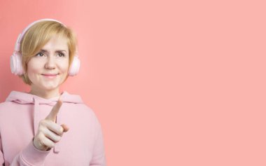 Pembe kazaklı beyaz bir kız ve arka planda pembe kulaklıklı ton olarak benzer. Müzik konsepti, podcastlar, sesli kitaplar. Dünya Müzik Günü, Dünya Rock-n-Roll Günü