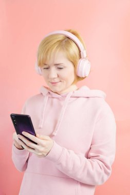 Pembe kazaklı beyaz bir kız ve arka planda pembe kulaklıklı ton olarak benzer. Müzik konsepti, podcastlar, sesli kitaplar. Dünya Müzik Günü, Dünya Rock-n-Roll Günü