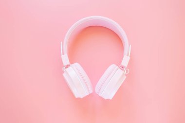 Pembe arka planda pembe kulaklıklar. Müzik konsepti, podcastlar, sesli kitaplar. Üst görünüm, alanı kopyala.