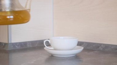 Kadın elleri çay fincanı ve çay tabağına demlenmiş çay doldurur. Çay içme kavramı, bitkisel sağlıklı çay..