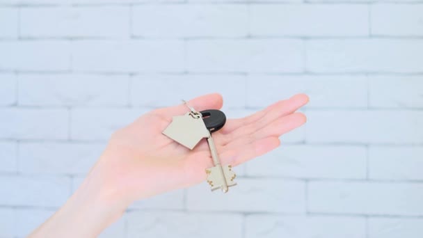 钥匙在一个女人的手里 带着一个房子形状的钥匙链 购买住房 抵押贷款 房地产 年轻家庭 住房贷款 出租住房的概念 — 图库视频影像