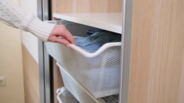 Kadın dolaptaki çekmeceden temiz kot pantolon çıkardı. Gardırop, tarz, giysi konsepti, sıradan. Uzayın Düzeni.