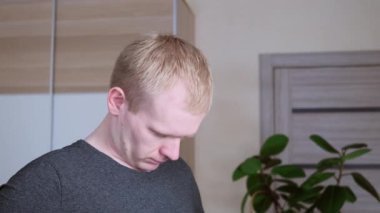 Eğitimden önce genç, beyaz, sarışın erkek boynunu yoğuruyor. Evde spor konsepti, tecrit.