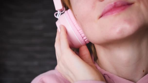 Menina Caucasiana Uma Camisola Rosa Com Fones Ouvido Rosa Fundo — Vídeo de Stock