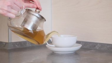 Kadın elleri çay fincanı ve çay tabağına demlenmiş çay doldurur. Çay içme kavramı, bitkisel sağlıklı çay.