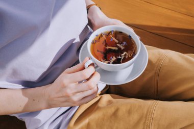 Beyaz fincan bitkisel çay ve kadın ellerinde bir fincan çay. Çay içme, sağlıklı içecekler..