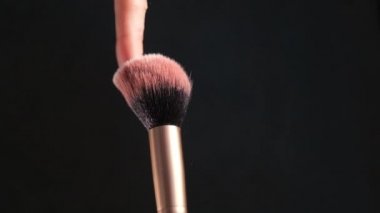 Farklı yönlere etkili bir şekilde yayılan fosforlu kalemle makyaj fırçası. Karanlık arka plan, minimalizm, kopyalama alanı. Makyaj, kozmetik, imaj konsepti.