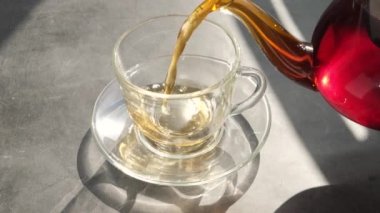 Taze aromatik bitkisel çay şeffaf bir fincana dökülür. Sıcak sıcak vitamin ve sağlıklı içecekler konsepti.