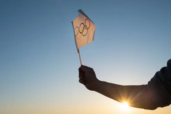 Ολυμπιακή Σημαία Μικρή Στο Χέρι Κυματίζει Στο Φόντο Του Γαλάζιου — Φωτογραφία Αρχείου