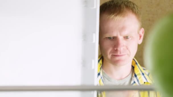 Молодой Белый Блондин Клетчатой Желтой Рубашке Открывает Холодильник Заглядывает Внутрь — стоковое видео
