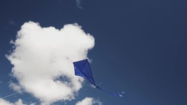 Mavi bir uçurtma gökyüzünde süzülüyor. Özgürlük kavramı, yaz hobileri, doğada eğlence. Minimalizm, metin için alan, mavinin tonları.
