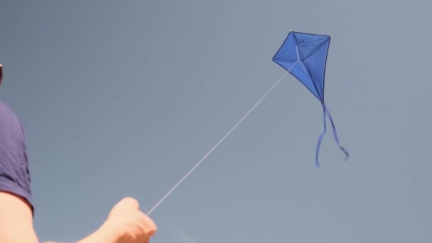 青い空に青い凧が舞い上がる 男はカイトを支配する 夏の趣味 自然の中でのエンターテイメントの概念 ミニマリズム テキストのためのスペース 青の色合い — ストック動画