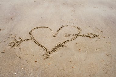 Bir kalp kum plaj üzerinde çizim.