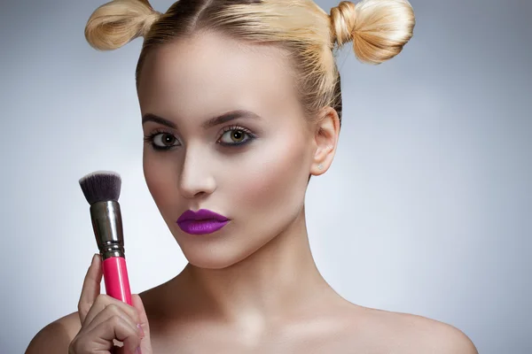 Portret van het meisje met een lichte make-up professional. Een meisje met een borstel. — Stockfoto