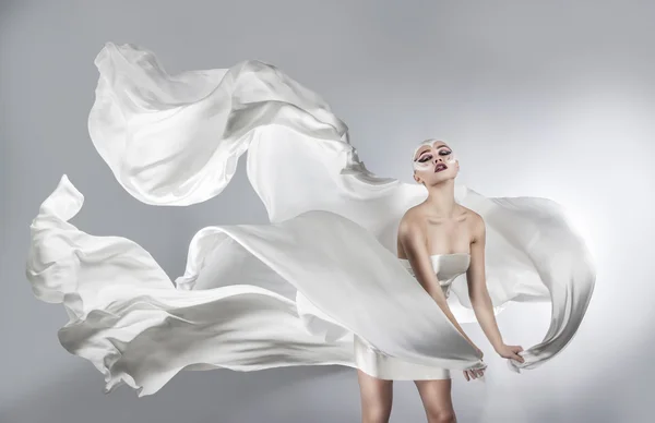 Mulher com maquiagem criativa brilhante em um pano branco voando. Uma menina segurando um pano branco voador — Fotografia de Stock