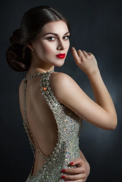 Hermosa joven con un vestido de noche de cristal. Belleza perfecta, labios rojos, maquillaje brillante. Brillantes piedras brillantes en el vestido — Foto de Stock