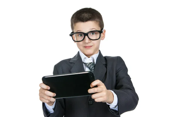 Sorprendido y sorprendido niño colegial con gafas. Niño inteligente con una tableta en las manos . —  Fotos de Stock