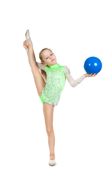 Niña linda gimnasta con una pierna muy elevada. Escisiones verticales . — Foto de Stock