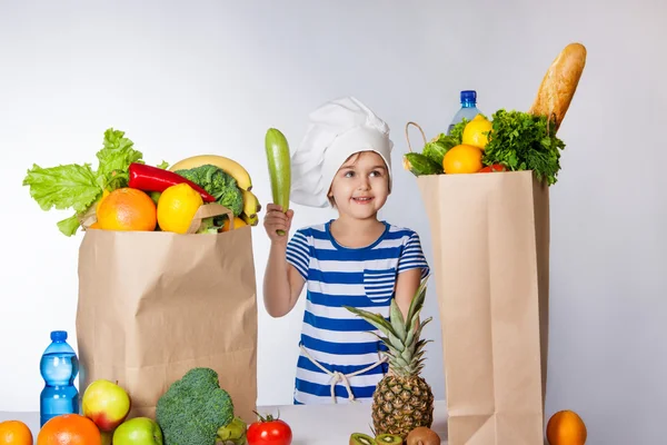 Little happy girl in chef hat with big bags of fruits and vegetables Positive human emotion, facial expression feeling, attitude — Stock Image Little happy girl in chef hat with big bags of fruits and vegetables Positive human emotion, facial expression feeling, attitude Stock Picture