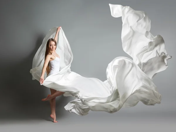 Beautiful young girl dancing. The girl in flying white dress. A white cloth is flying in the air. White light dress — Stock Photo, Image