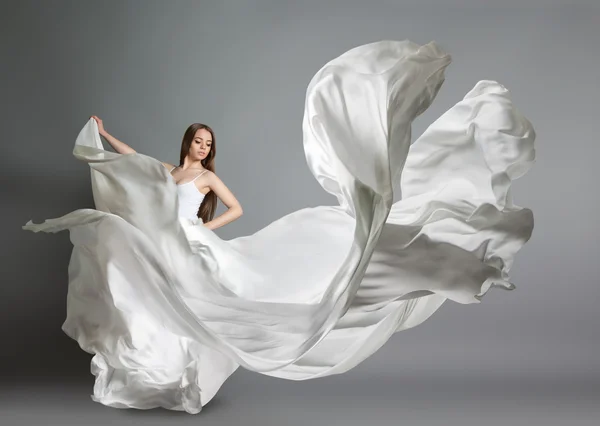 Piękna młoda dziewczyna taniec. Dziewczyna w białej sukni latające. Białe płótno leci w powietrzu. Białe światło sukienka — Zdjęcie stockowe