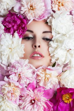Çiçeklerle çevrili genç güzel kadın yüzü. Peonies portre.
