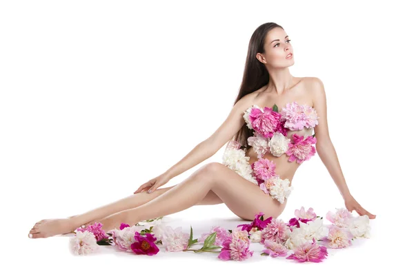 Молода красива жінка з півоніями. Дівчина сидить на підлозі з квітами. Квіти покривають тіло . — стокове фото